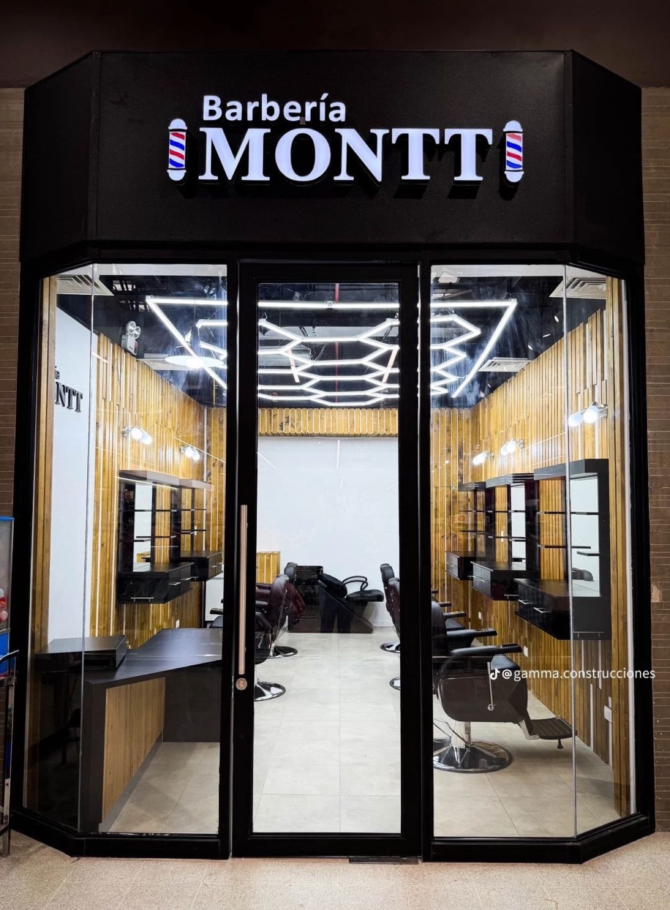 Fachada de Barbería Montt con su letrero iluminado